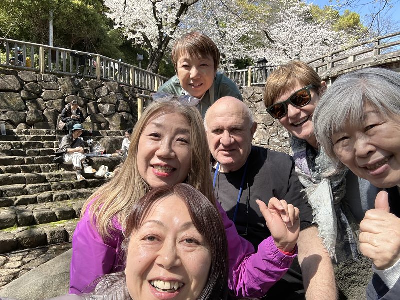 A group selfie with the guides beside the river in cherry blossom season