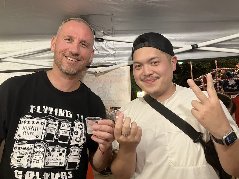 A guest and a guide toasting at a night food stall
