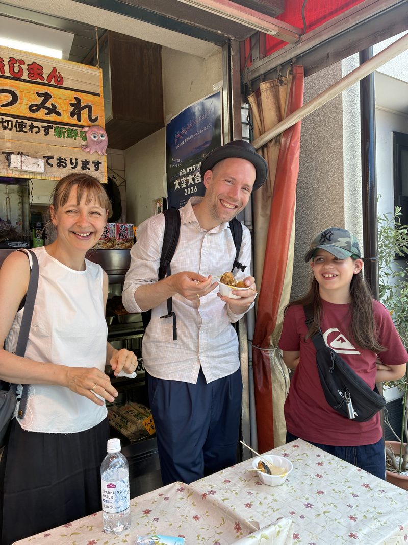Guests trying fish-cake snacks at a shop in a Tokyo shopping street