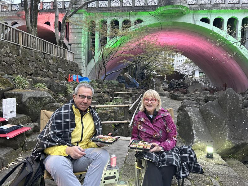 Guests with bento boxes at a private hanami spot beside the Otonashi river