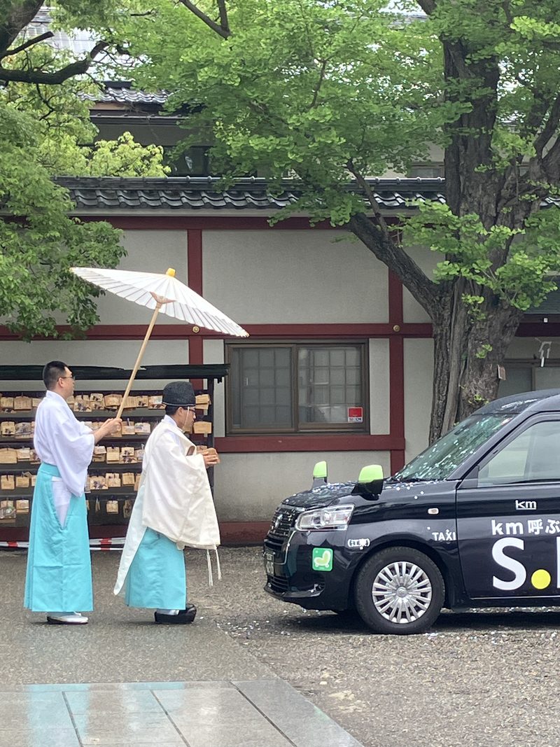 Shinto priests walking under a white parasol at a Tokyo shrine